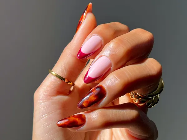 A hand showcasing manicure with stylish fallthemed gel nail designs