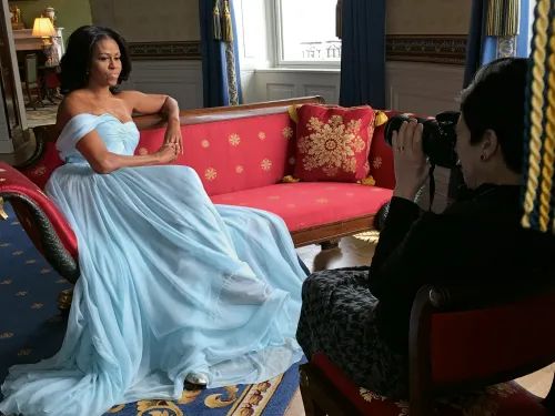 Michelle Obama sitting in a formal pose on a red sofa during a photoshoot