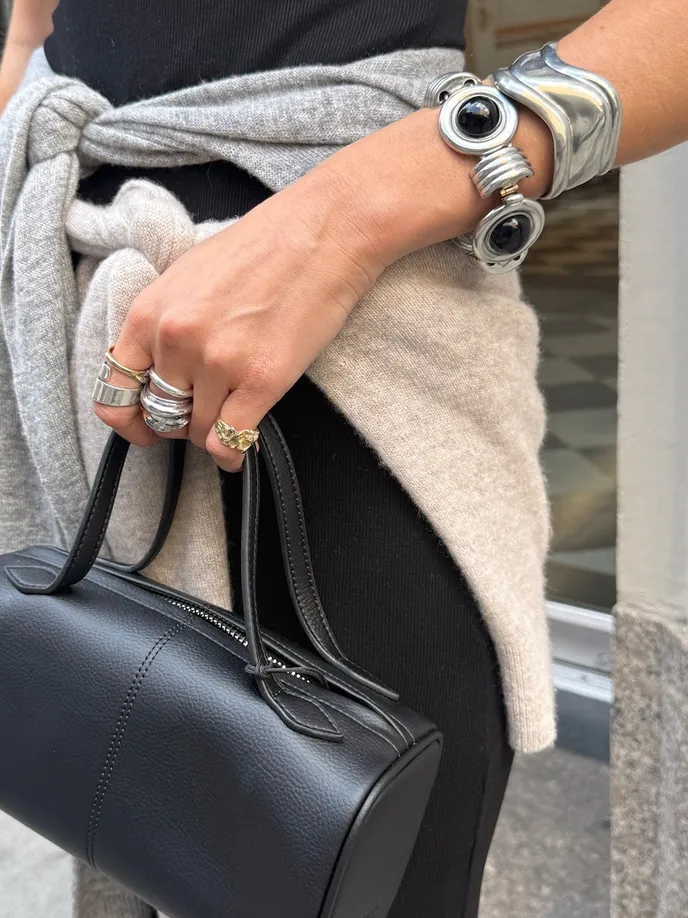 woman with oversize bangle bracelets and black hand bag